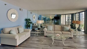 Ein geräumiges Wohnzimmer mit zwei Sofas, einem Couchtisch und einem großen Spiegel, der den Raum reflektiert.