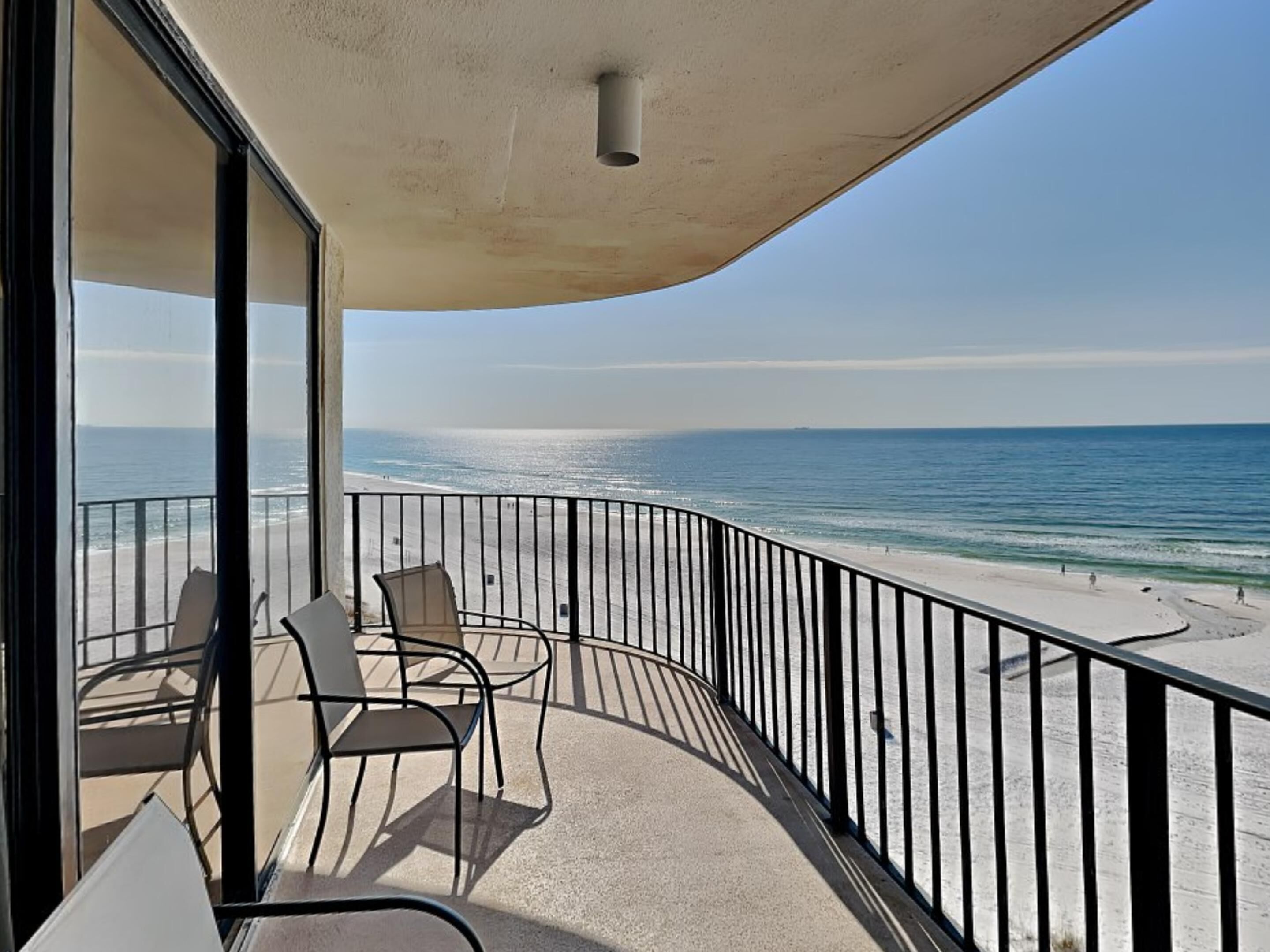 A balcony with a view of the beach and ocean.