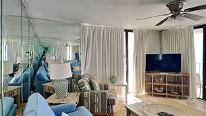 A modern living room with a sofa, TV, and a ceiling fan. - Edgewater Tower III #501 | Amenities Galore! (Panama City Beach)