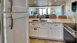 A modern kitchen with white cabinets, a stainless steel sink, and a built-in oven.