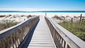 A wooden boardwalk leading to a beach with clear skies.