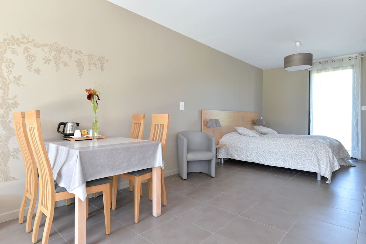 A room with a dining table, chairs, a bed, and a lamp.