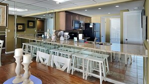 A modern kitchen with a central island, bar stools, and a dining table.
