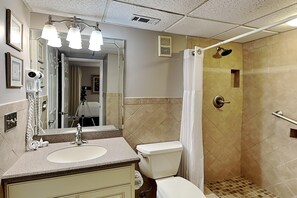 A bathroom with a sink, toilet, shower, and a mirror.