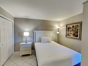A bedroom with a bed, nightstand, lamp, and a painting on the wall.