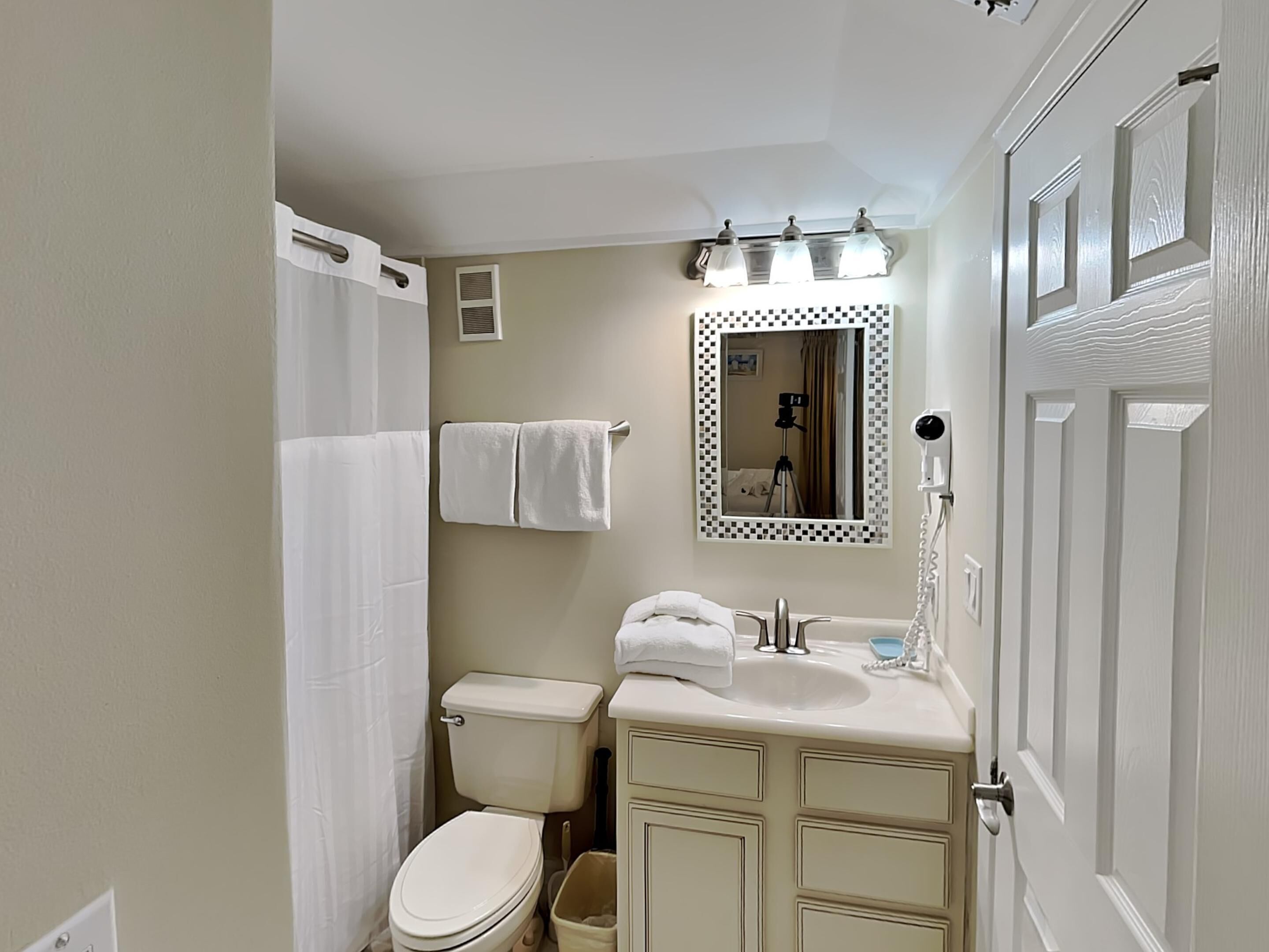 A bathroom with a toilet, sink, and mirror.