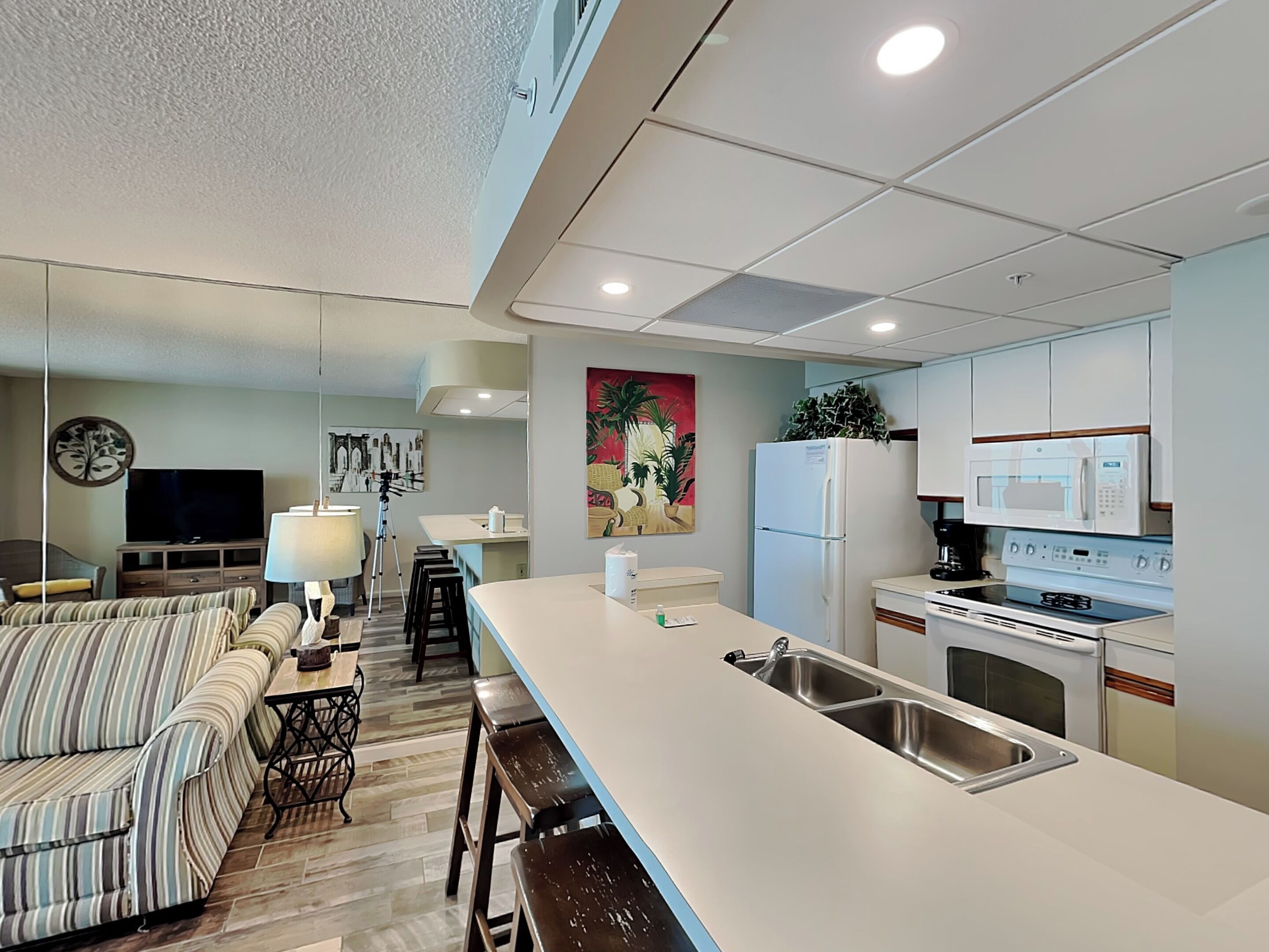 Una cocina moderna con una isla central, armarios blancos y electrodomésticos de acero inoxidable.