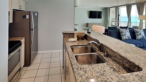 A modern kitchen with granite countertops, stainless steel sinks, and a built-in oven.