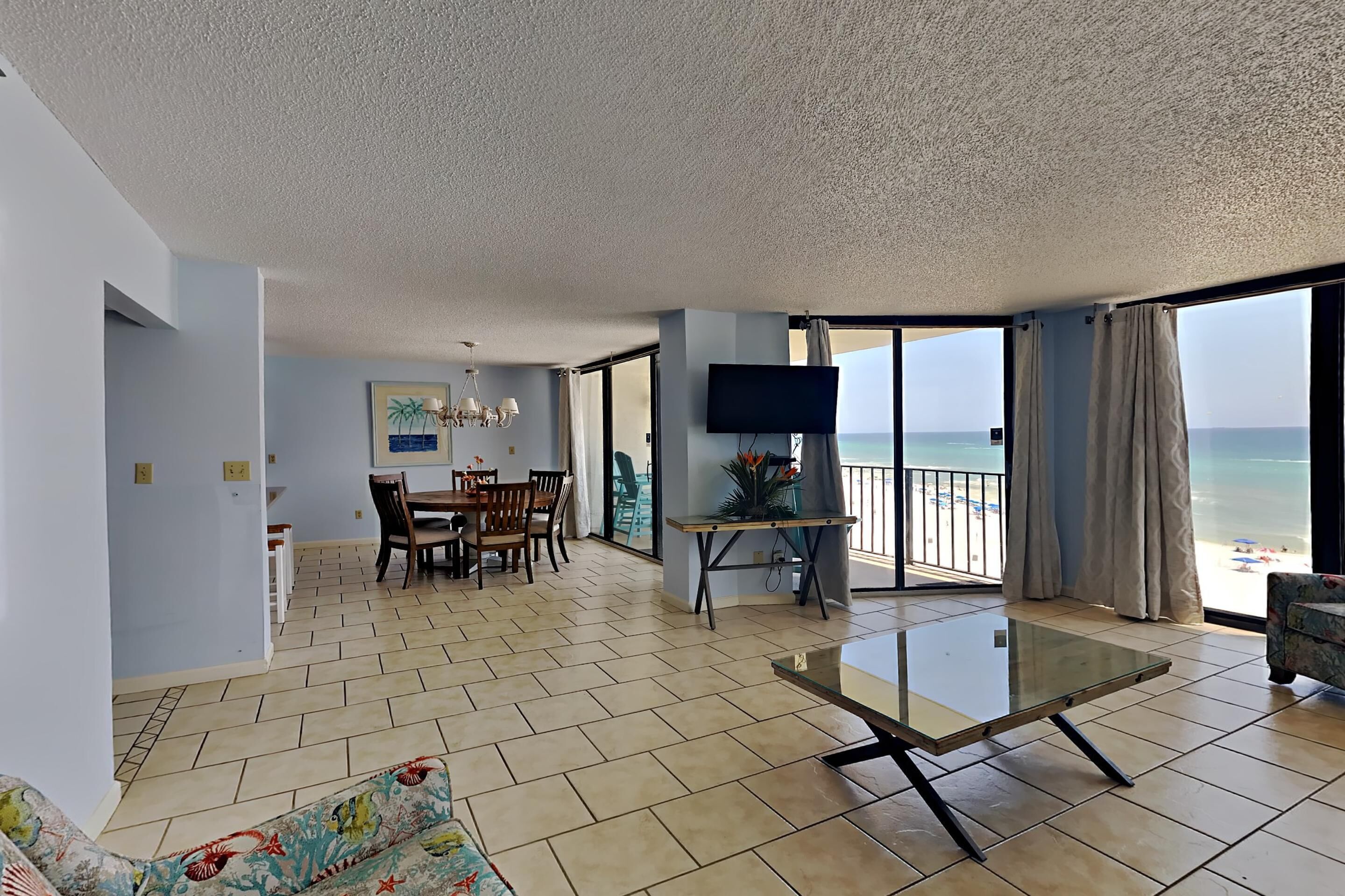 A spacious living area with a glass table, a dining set, and a TV.