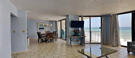 A spacious living area with a glass table, a dining set, and a TV.