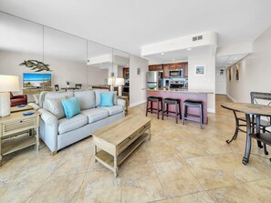 A modern living room with a sofa, coffee table, and kitchen area with bar stools.