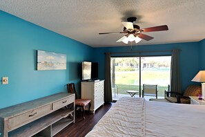 Quarto com cama, escrivaninha, penteadeira, televisão e vista para um campo de golfe pela janela.