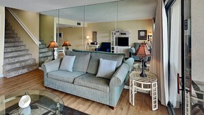 Un salon avec un canapé, une table basse en verre, une lampe et un meuble pour la télévision.
