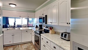 A compact kitchen with white cabinets, a microwave, a toaster, and a coffee maker.