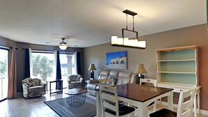 Un vaste espace de vie comprenant une table à manger, des chaises, un canapé et un ventilateur de plafond.
