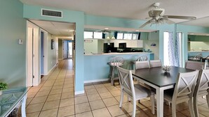 A spacious kitchen with a dining area, a ceiling fan, and a view of the adjacent living room. - Edgewater Villa #1501 | Golf Course View! (Panama City Beach)