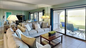 A modern living room with a sofa set, a coffee table, and a TV. - Edgewater Villa #1501 | Golf Course View! (Panama City Beach)