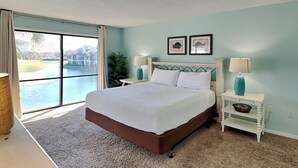 Un dormitorio con una cama grande, vistas a un cuerpo de agua y una ventana con cortinas.