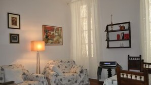 Un salon avec un canapé, une lampe, une bibliothèque et un tableau accroché au mur.