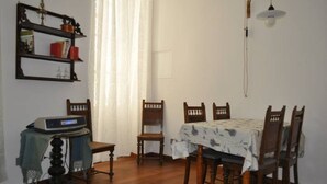 Une salle à manger avec une table en bois, des chaises, un lustre et une bibliothèque.