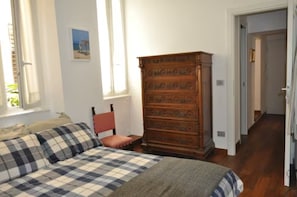 A bedroom with a bed, a wooden dresser, a chair, and a window.
