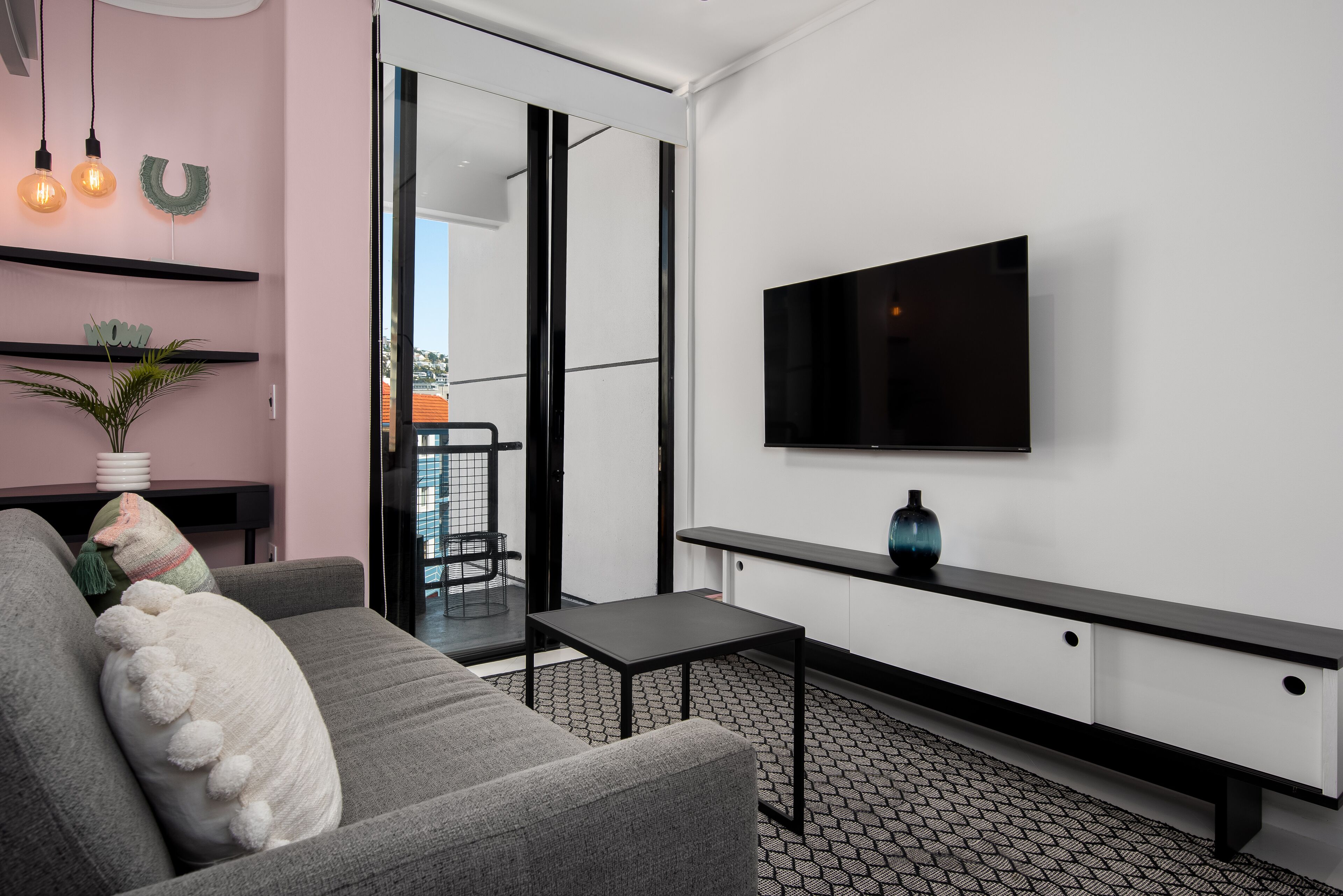 Ein modernes Wohnzimmer mit einem grauen Sofa, einem schwarzen Couchtisch und einem flachbildfernseher an der Wand.