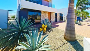 Un edificio moderno de dos plantas con grandes ventanales, fachada de ladrillo y entrada pavimentada.