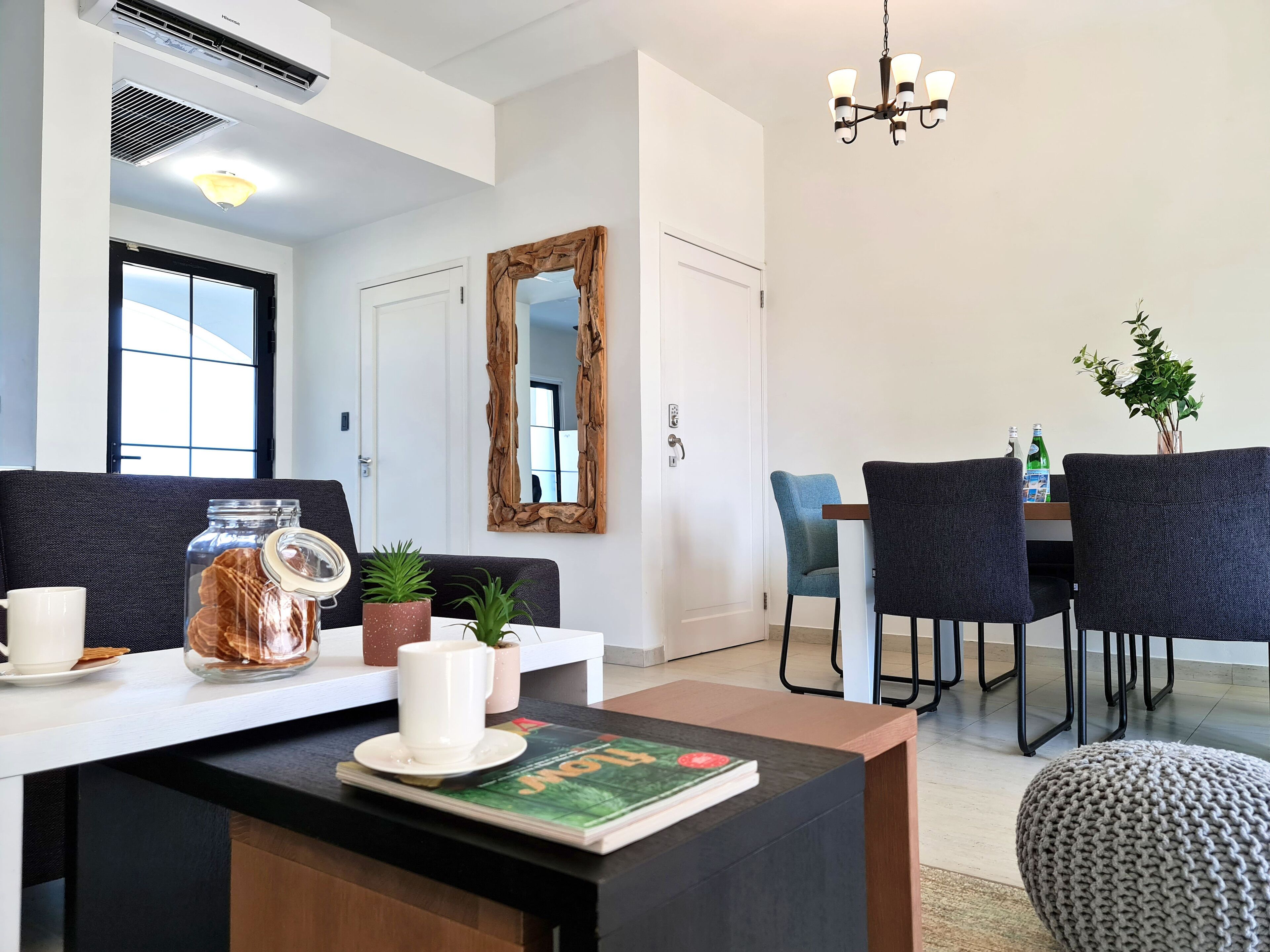 Una sala moderna con una mesa de centro, una revista, un espejo y un comedor con sillas y una mesa.