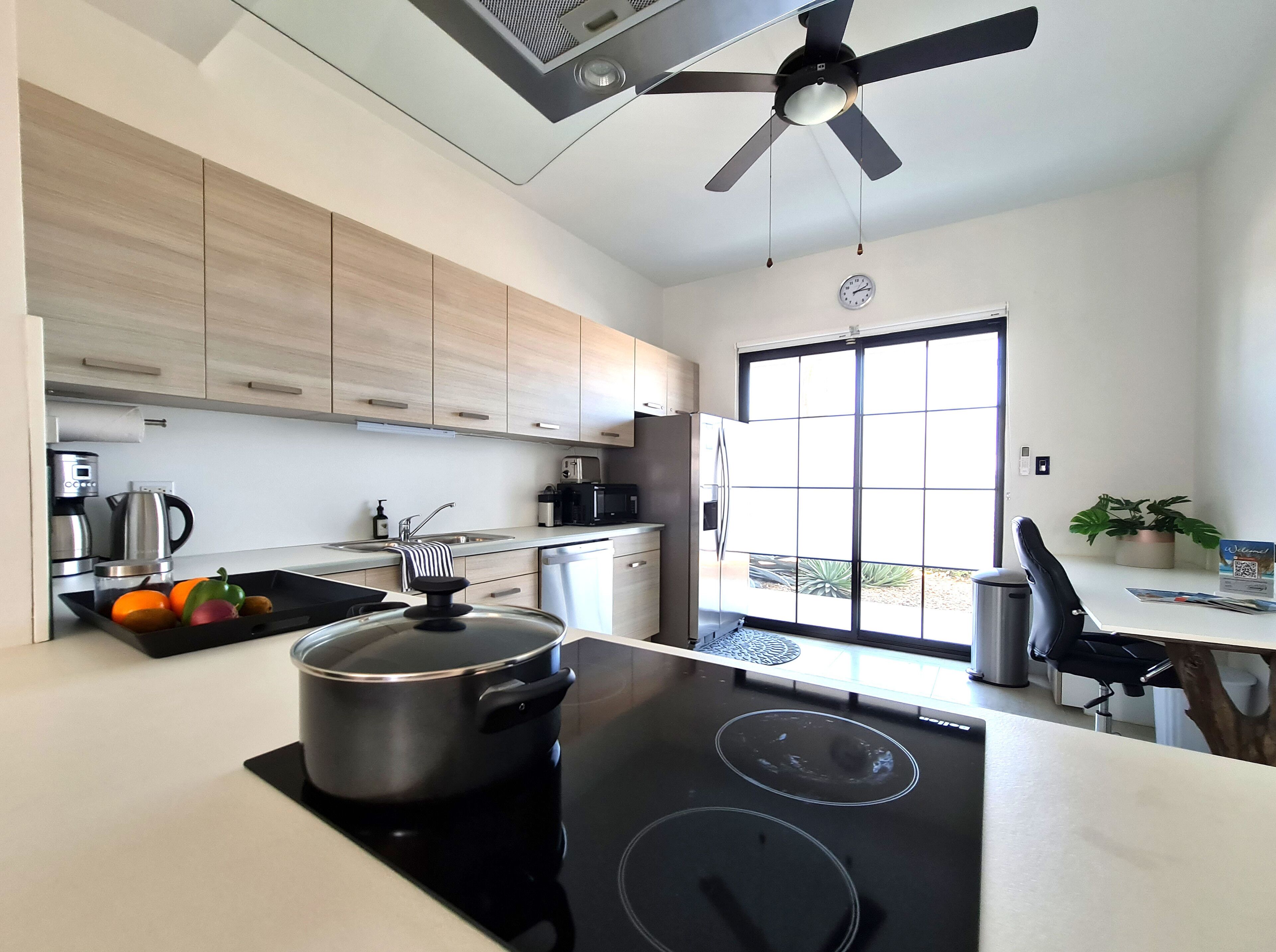 A modern kitchen with a black stove, a pot on the counter, a coffee maker, and a sink.
