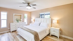 A bedroom with a bed, nightstands, a ceiling fan, and a window. - AMAZING HOUSE NEAR THE BEACHES OF SOUTH FLORIDA (Cape Coral)