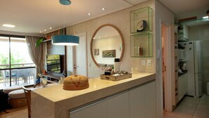 A modern kitchen with a marble countertop, a round mirror, and a built-in refrigerator.