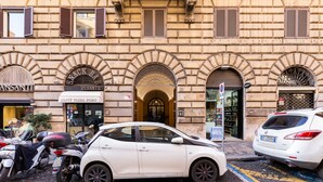Un edificio con una tienda llamada "Caffè Tazza Doro" y un coche blanco estacionado en la parte delantera.