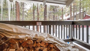A covered wooden deck with a stack of firewood and a smoking sign. - Mammoth Lakes Condo ~ 5 Mi to Mammoth Mtn! (Mammoth Lakes)