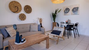 A modern living room with a sofa, coffee table, and a dining area with chairs and a table. - PP 6/40, a bedroom apt in a complex with communal pools at Plakias (Plakias)