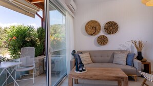 A modern living room with a glass door leading to a balcony, a wooden coffee table, a sofa, and decorative wall art. - PP 6/40, a bedroom apt in a complex with communal pools at Plakias (Plakias)