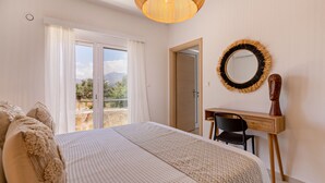 A bedroom with a bed, a desk, a chair, a mirror, and a view of the outdoors. - PP 6/40, a bedroom apt in a complex with communal pools at Plakias (Plakias)