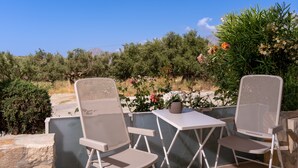 Two outdoor patio chairs and a small table with a vase, set against a backdrop of greenery and a clear sky. - PP 6/40, a bedroom apt in a complex with communal pools at Plakias (Plakias)
