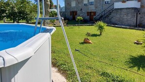 A swimming pool with a ladder, a stone building with a red-tiled roof, and a grassy yard. - Rural farm - Queen room with breakfast (Viana do Castelo)