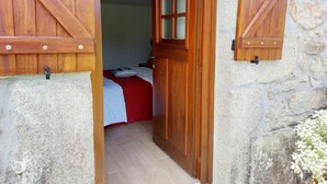 A room with a bed, a wooden door, and a stone wall. - Rural farm - Queen room with breakfast (Viana do Castelo)