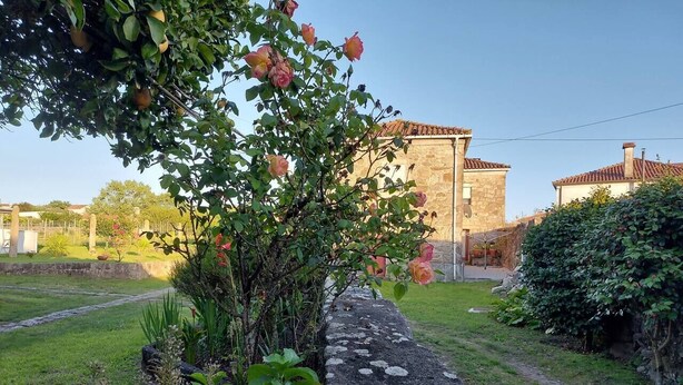 A stone wall with a garden path, a stone building, and a clear sky. - Rural farm - Queen room with breakfast (Viana do Castelo)