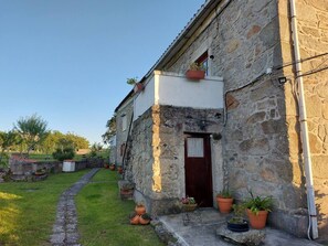 A stone building with a small porch, potted plants, and a pathway leading to the entrance. - Rural farm - Queen room with breakfast (Viana do Castelo)