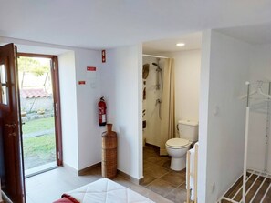 A room with a bed, a fire extinguisher, a wicker basket, a shower, and a toilet. - Rural farm - Queen room with breakfast (Viana do Castelo)
