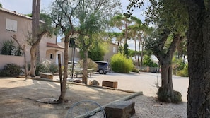 A parking area with a car, trees, and a building in the background.