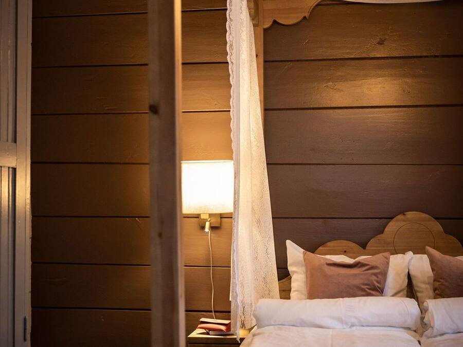 Un dormitorio acogedor con cabecera de madera, cama con dosel, lámpara de noche y lámpara colgante.