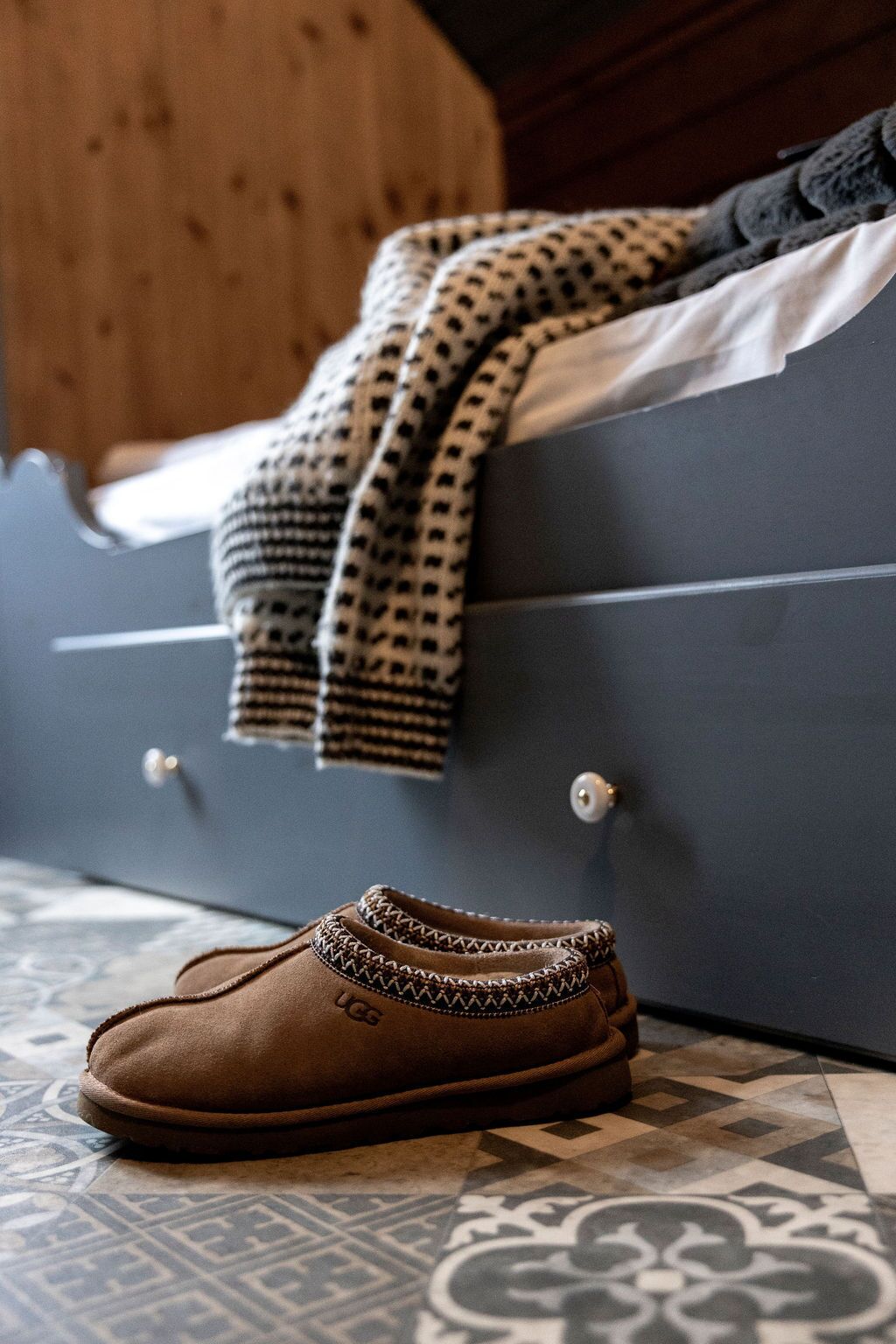 Una cama con un edredón estampado y un par de zapatos en el suelo.