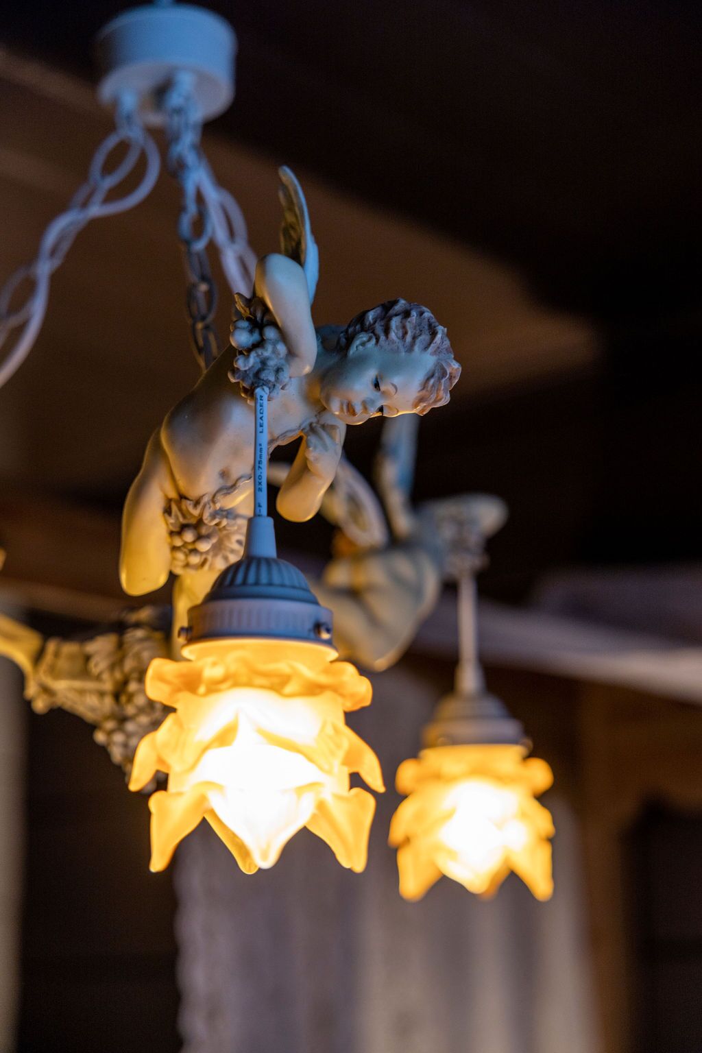 A chandelier with a decorative angel figure and a lit candle-like light fixture.