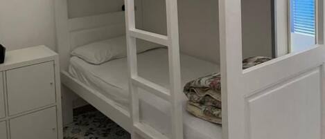 A bunk bed with a lower bunk and a small cabinet below it.