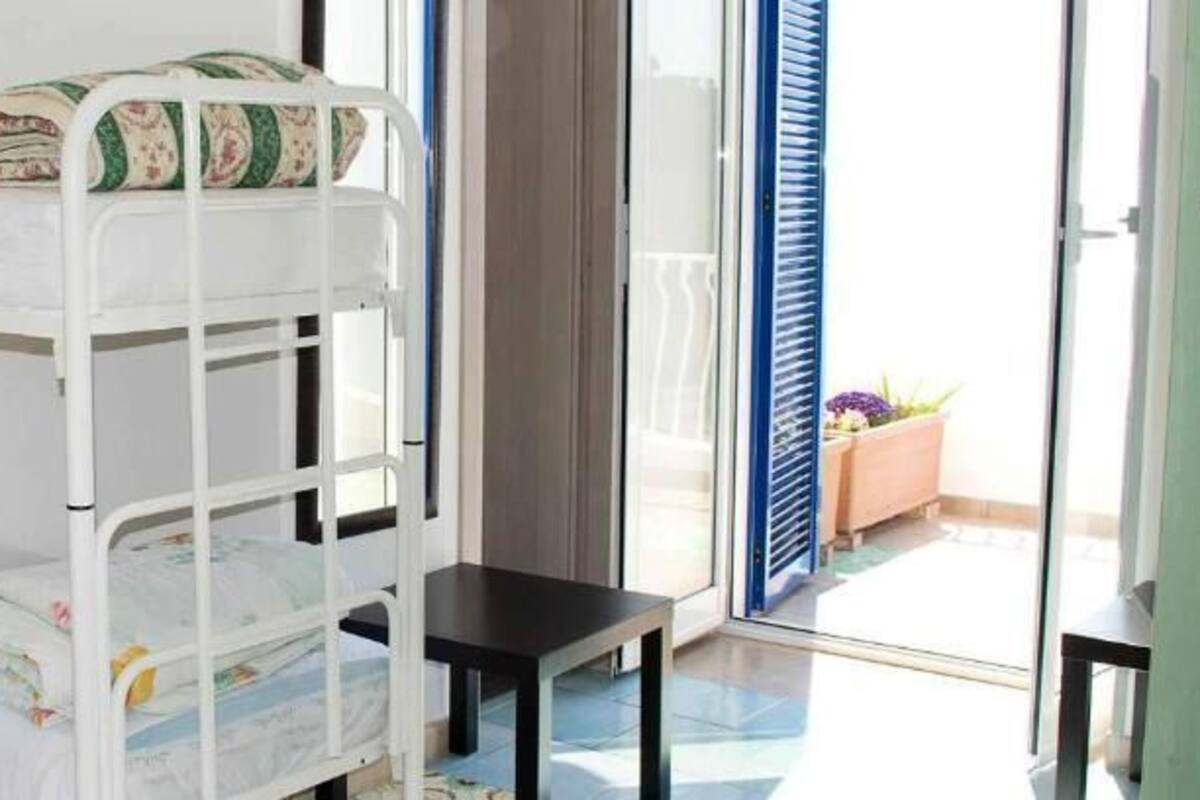 A bunk bed room with a small table and a window with blue shutters.