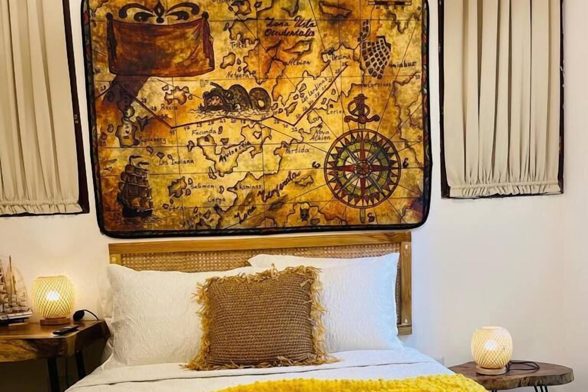 A bed with a large, ornate headboard, a yellow throw blanket, and a decorative pillow.