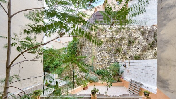 A courtyard with stone walls, potted plants, and a staircase. - Charming apartment located 10 min from the seaside (Marseille)